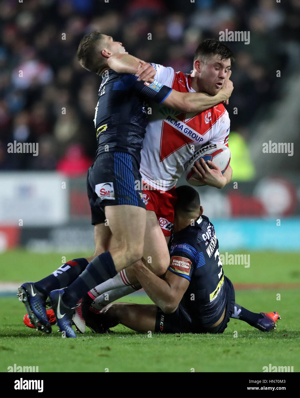 St Helens' Joe Greenwood è affrontato da Leeds Kallum Watkins (destra) e Matt Parcell durante la Super League match al totalmente Wicked Stadium, St Helens. Foto Stock