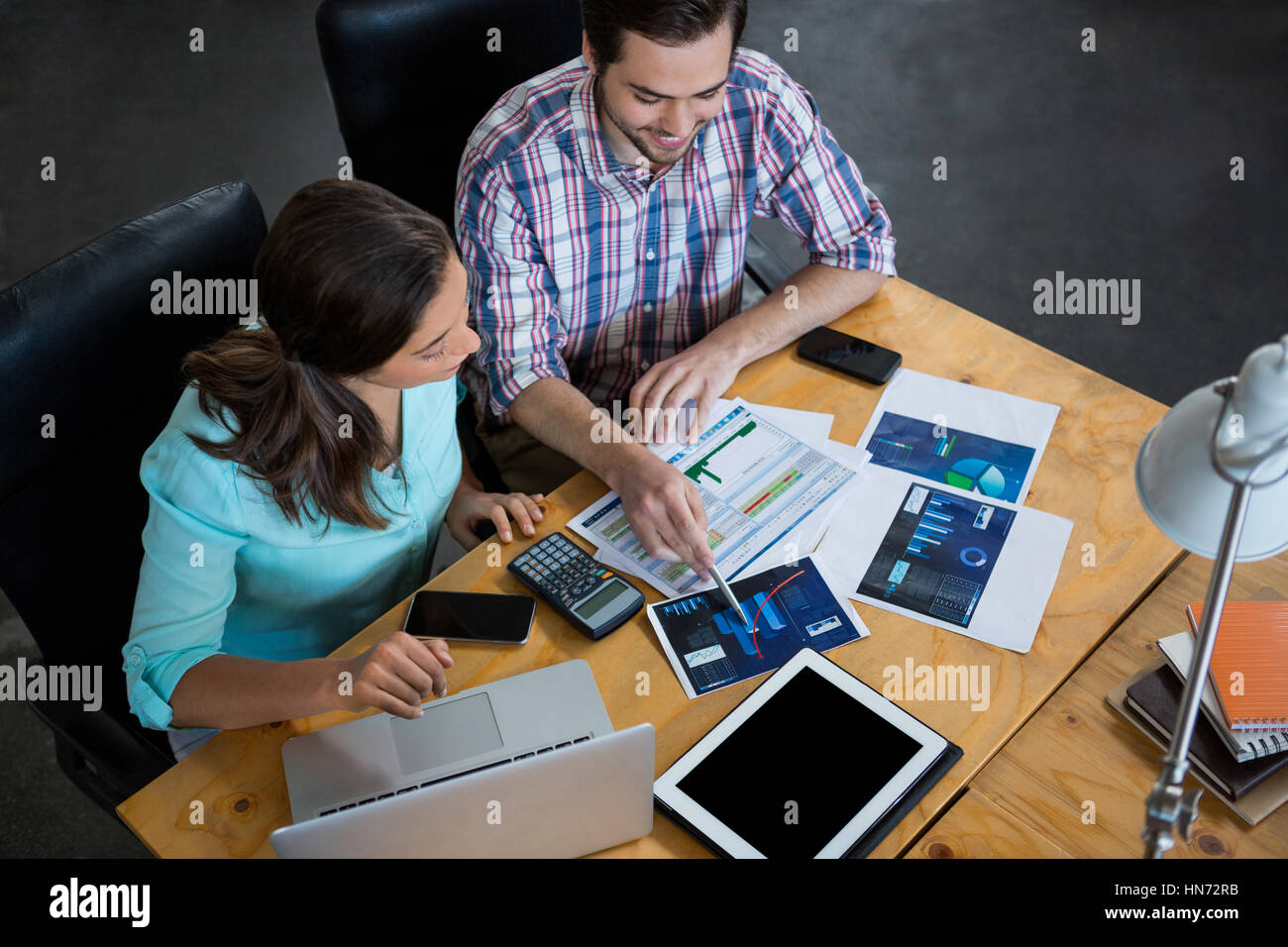 I dirigenti aziendali a discutere di tabelle e grafici sulla scrivania in ufficio Foto Stock