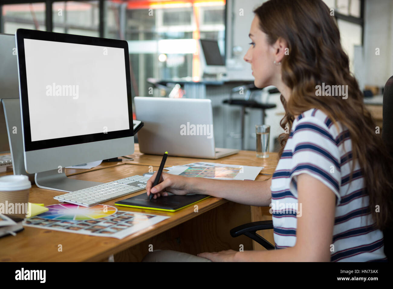 Femmina di graphic designer con tavoletta grafica alla scrivania in ufficio Foto Stock