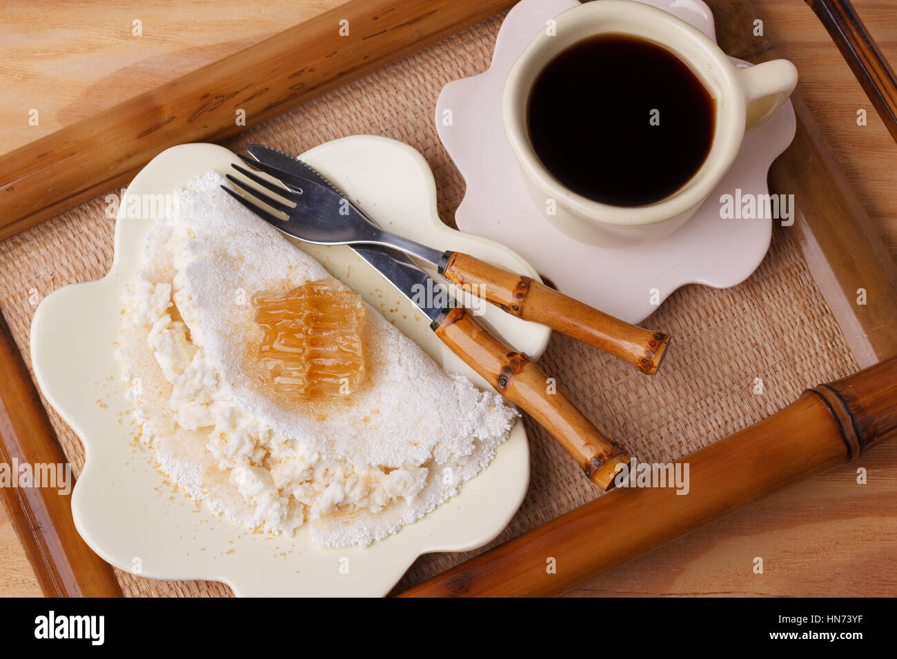 Casabe (ingaggiami, beiju, bob, biju) - flatbread di manioca (tapioca) con ricotta e miele e la tazza di caffè su sfondo di legno. Messa a fuoco selettiva Foto Stock