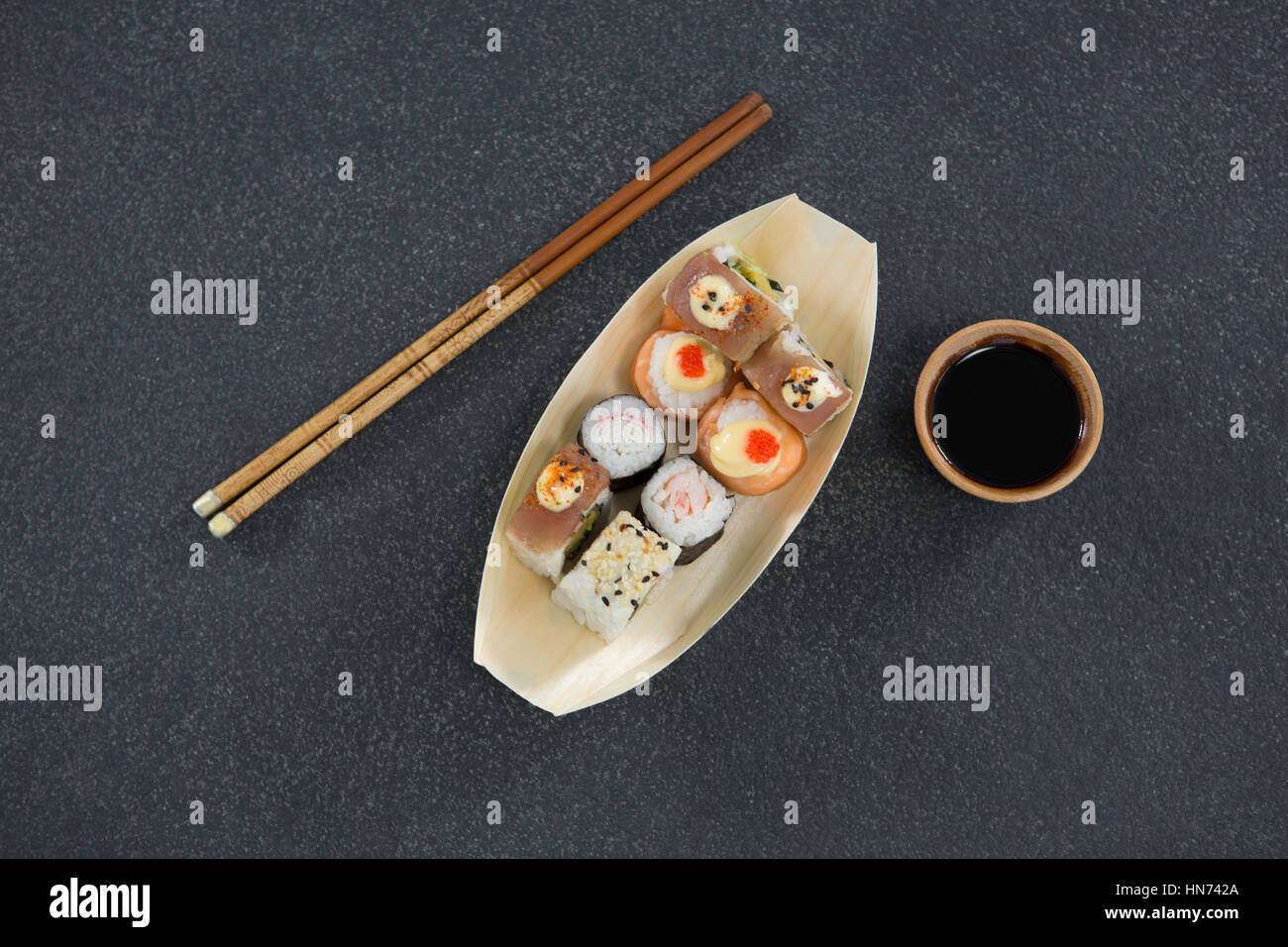 Sushi su imbarcazione piastra sagomata con bacchette e salsa Foto Stock