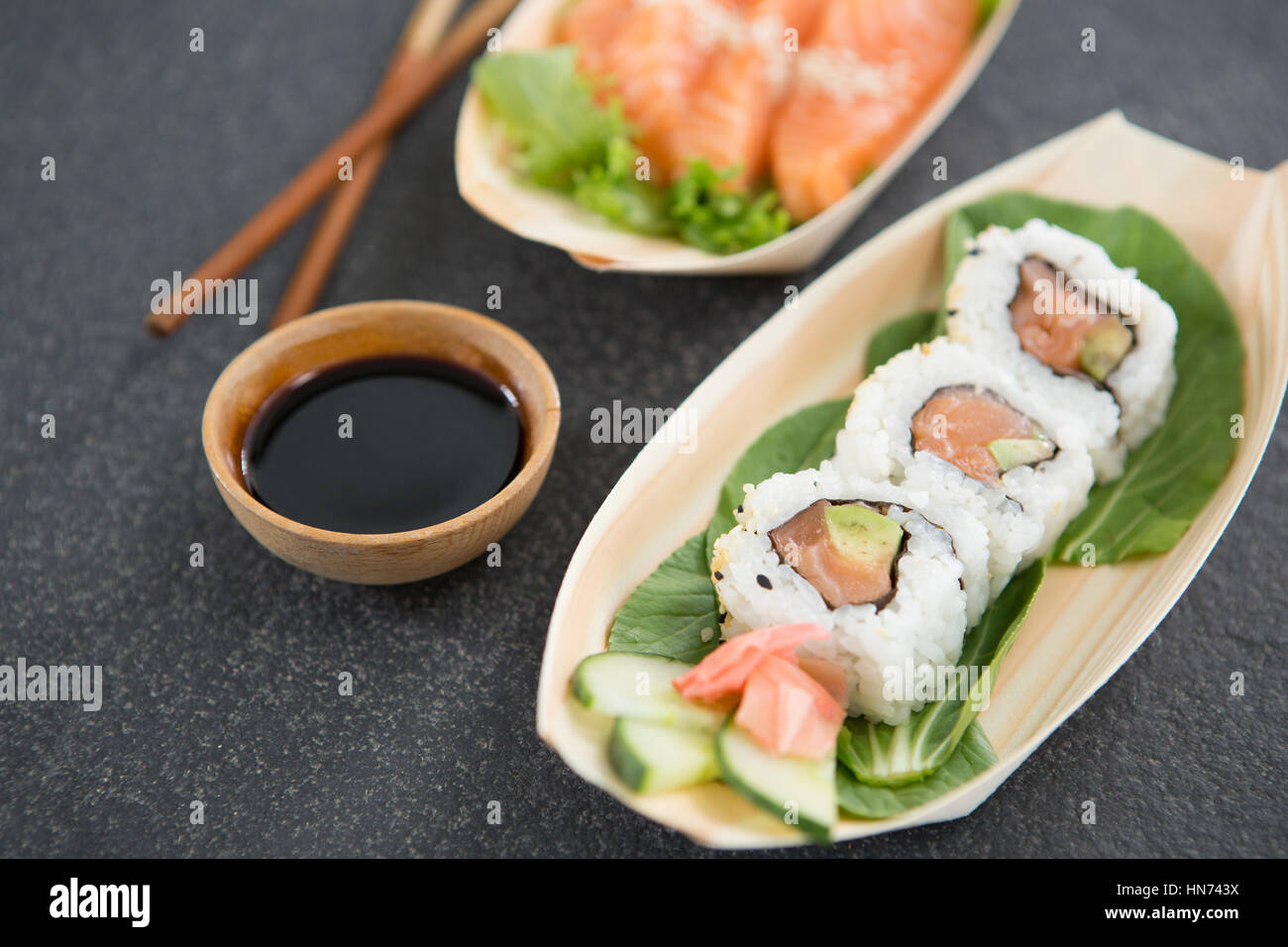 Sushi su imbarcazione piastra sagomata con bacchette e salsa Foto Stock