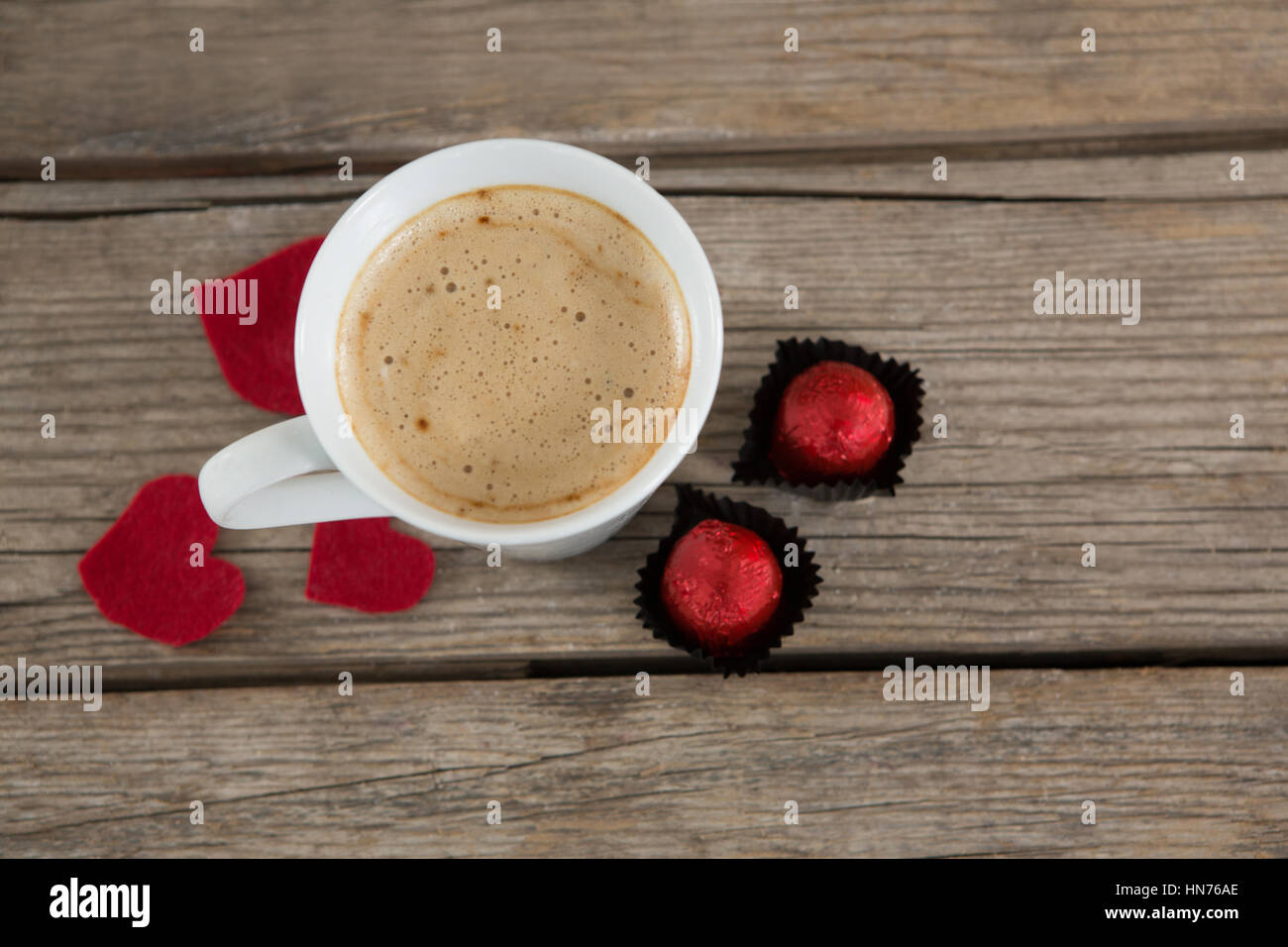 Tazza di caffè con cioccolatini e rosso dei petali di rosa su una superficie di legno Foto Stock