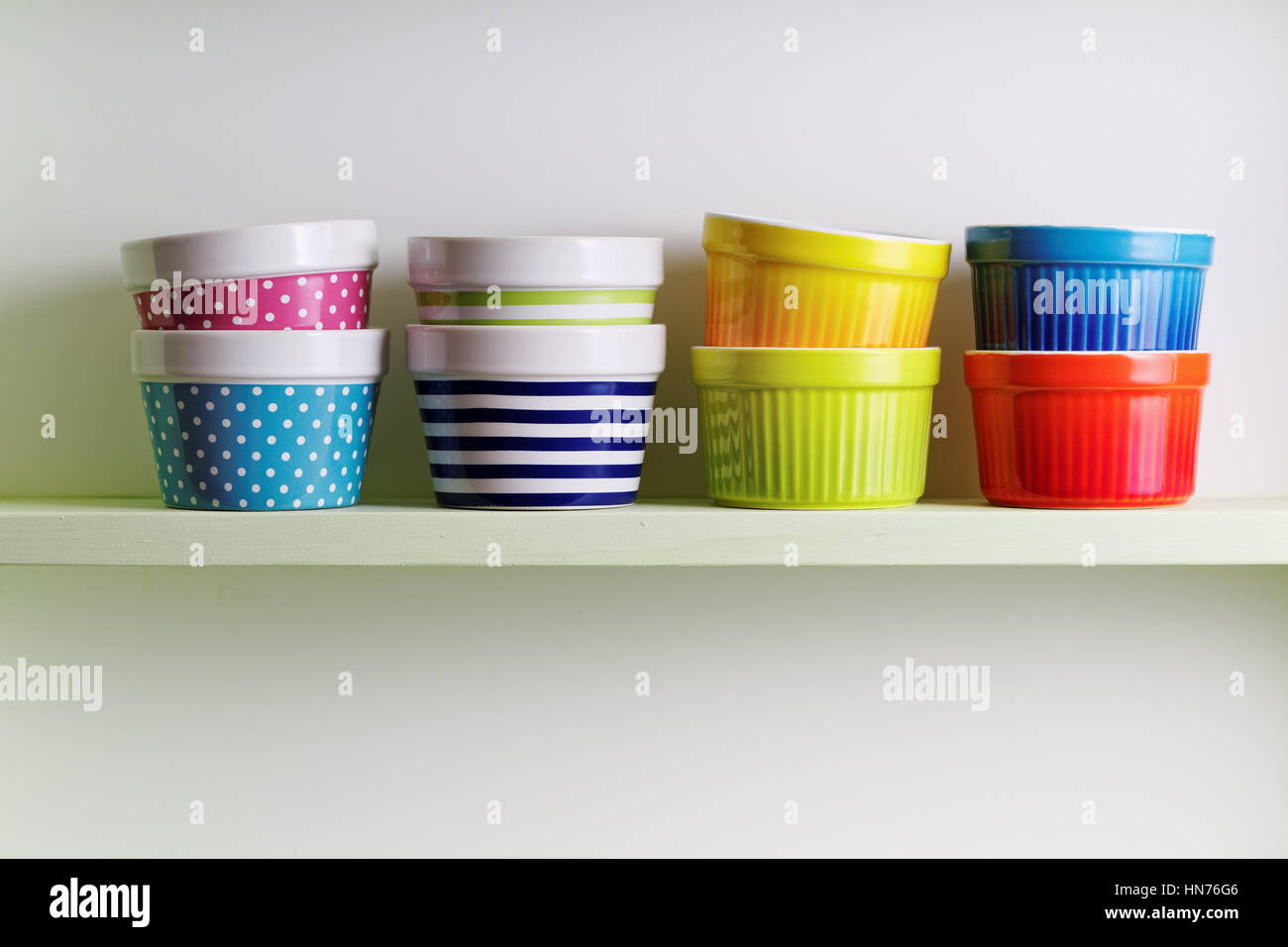 Tazze colorate su un ripiano della cucina. Una cucina scaffalatura tenendo a strisce e spotted bocce. Mensola da cucina disposizione. Foto Stock