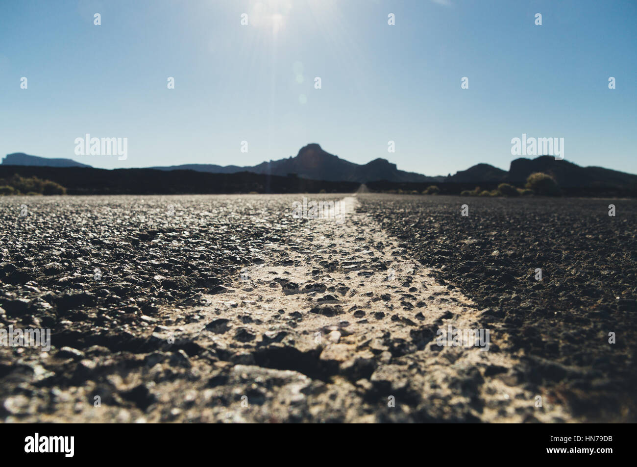 Vuoto strada nel deserto con silhouette di montagne sullo sfondo sunflares, dalla massa shot Foto Stock