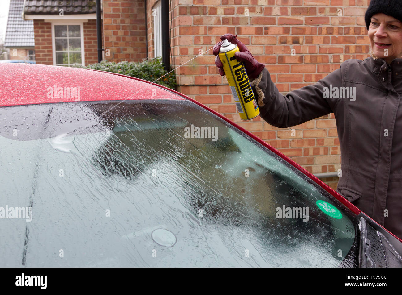 La donna lo sbrinamento finestrino di un'automobile con una bomboletta spray Foto Stock
