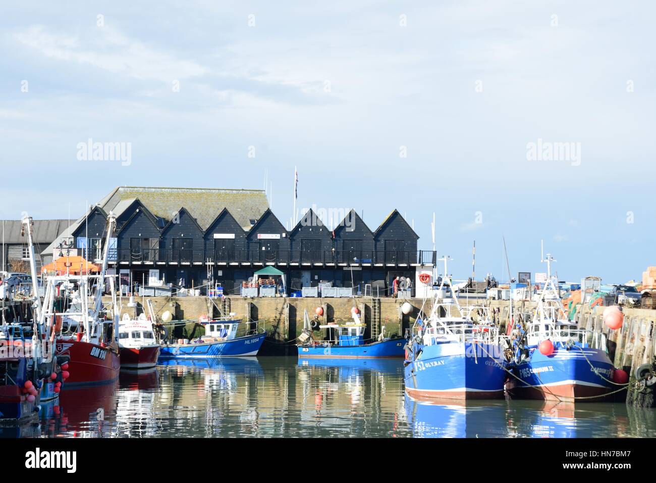Whitstable, Regno Unito - 1 Ottobre 2016: barche da pesca a Whitstable Harbour con fila di magazzini in background Foto Stock