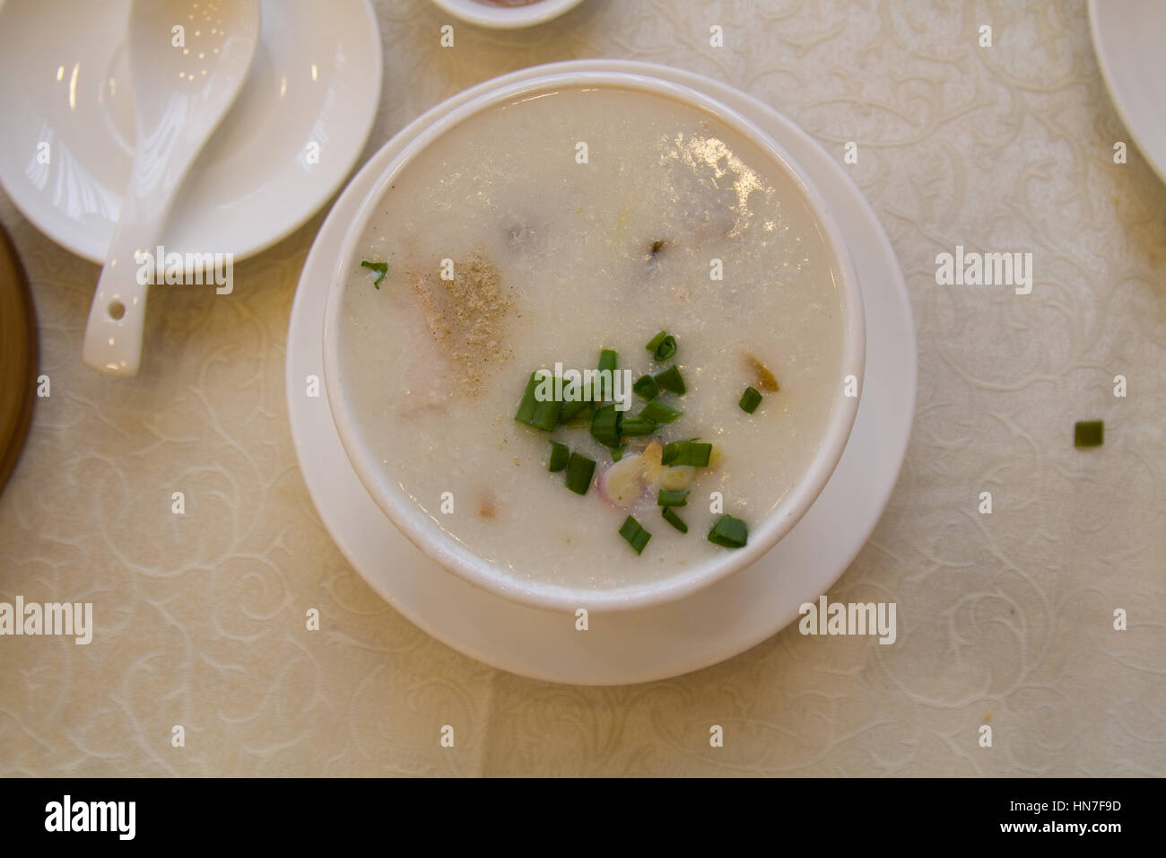 Congee o farinata di riso con coriandolo e versare in un ristorante vista dall'alto. Foto Stock