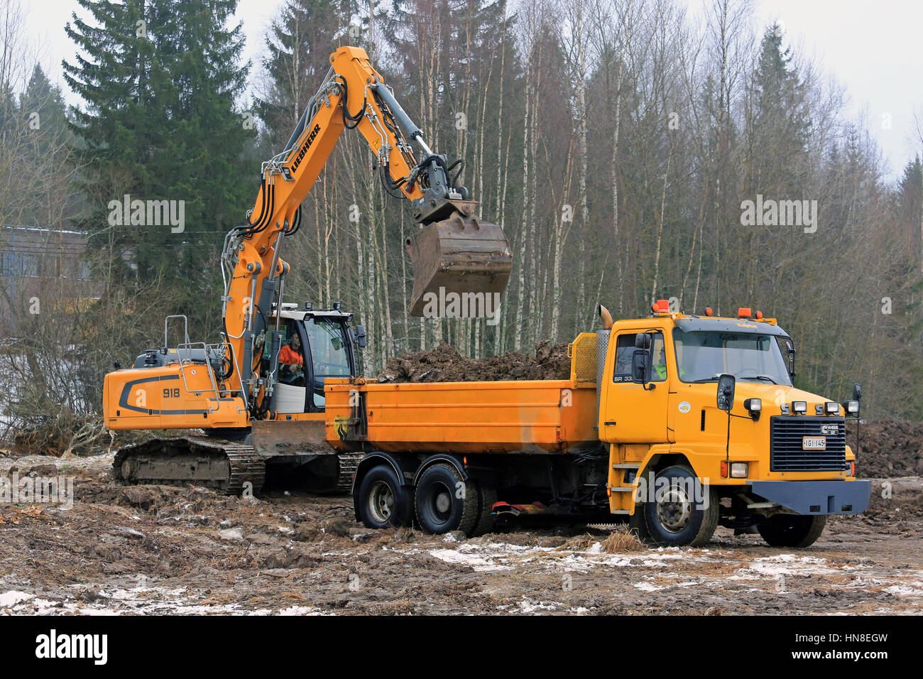 FORSSA, Finlandia - 28 gennaio 2017: Liebherr R 918 Escavatore cingolato carichi sul suolo giallo SR Sisu 332 carrello ribaltabile in inverno. Foto Stock