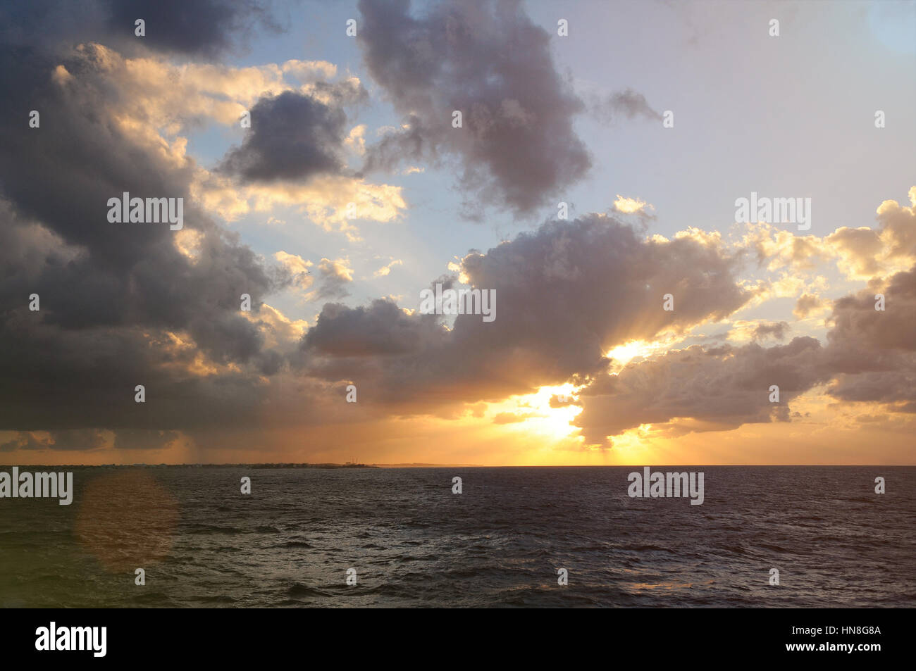 Tramonto sulla costa dell'oceano con raggi di sole venuto dal cielo molto nuvoloso Foto Stock