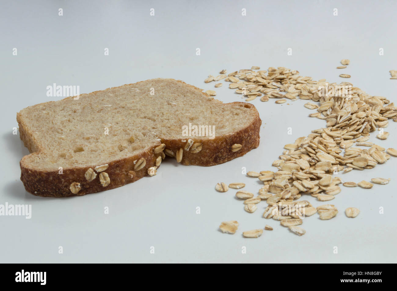 Tutto il frumento fetta di pane con avena su sfondo bianco Foto Stock