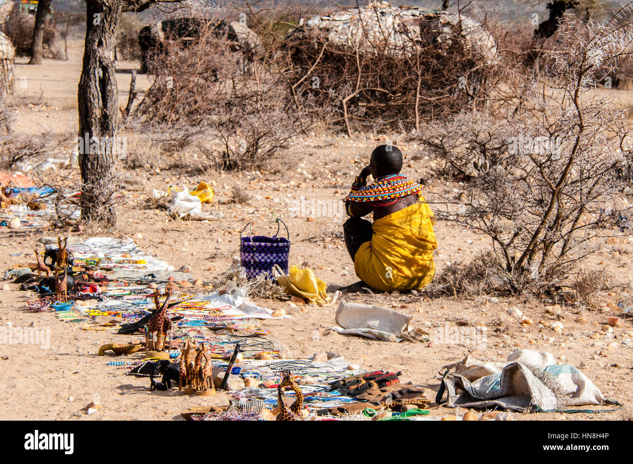 Un Samburu Maasai donna si siede sul terreno con gli oggetti artigianali che ella è la vendita a un villaggio nel Samburu, nel nord del Kenya, Africa orientale Foto Stock