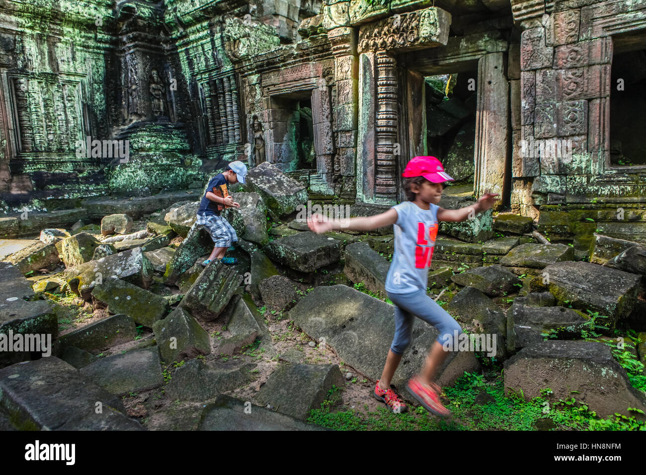 I bambini che giocano nel mezzo delle rovine del tempio nel cortile interno del Ta Prohm composto in Siem Reap, Cambogia. Foto Stock