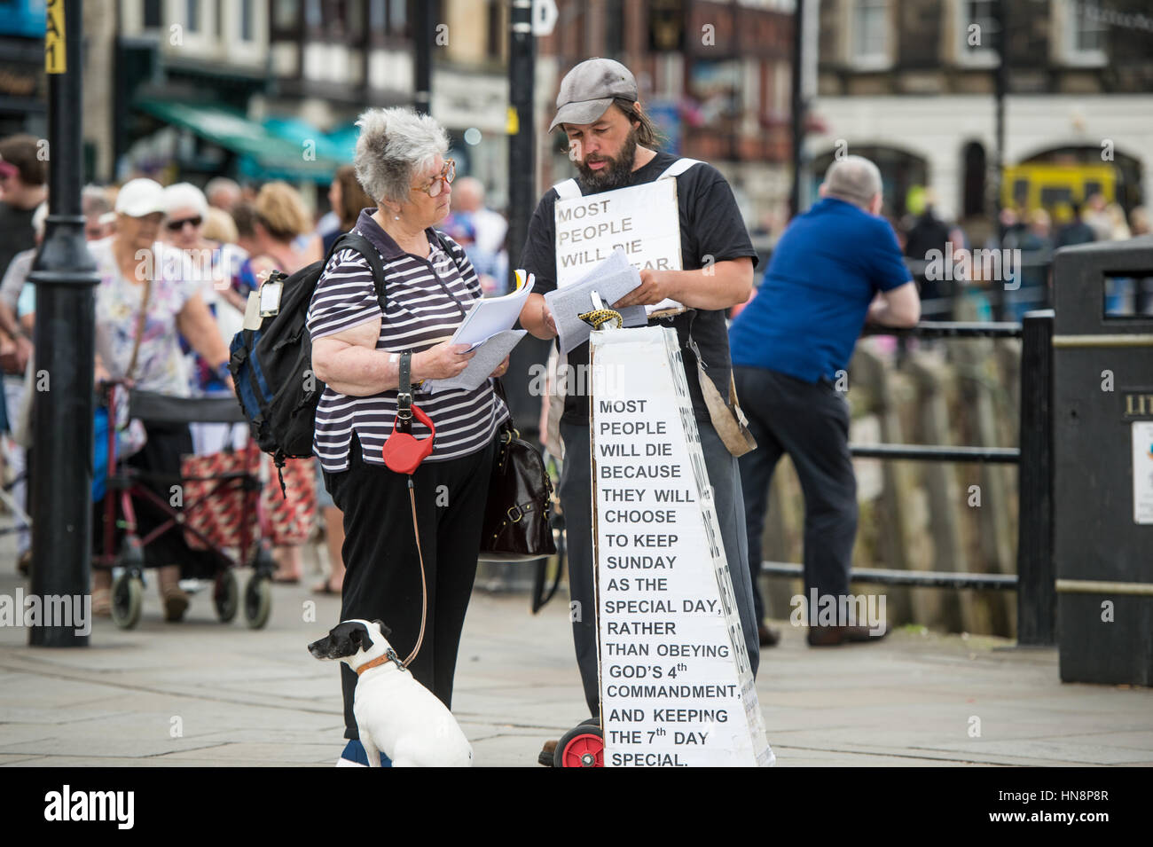 Regno Unito, Inghilterra, Yorkshire - due persone la lettura e la conversazione sulle credenze religiose in downtown Whitby, Inghilterra. Foto Stock