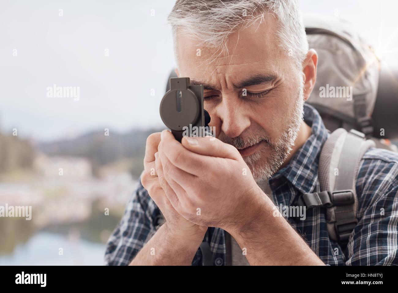 Escursionista trekking sulle montagne ed esplorando la natura, egli è utilizzando un escursionismo bussola e direzioni di ricerca Foto Stock