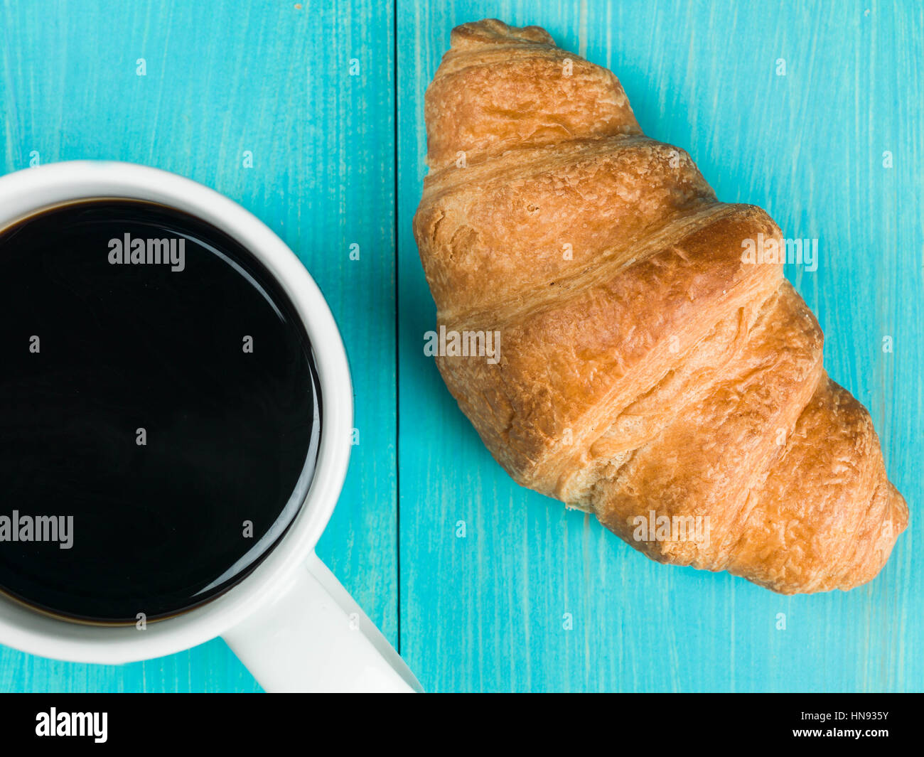 Preparato di fresco Mug a caldo di forte caffè nero con un fresco cotto Golden Brown prima colazione Croissant pronto a mangiare come un piatto con laici n. persone Foto Stock