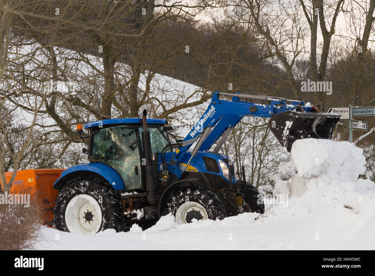 Il contadino si tenta di cancellare la neve profonda dopo una molto forti nevicate nelle zone rurali a Llangollen Galles del Nord Foto Stock