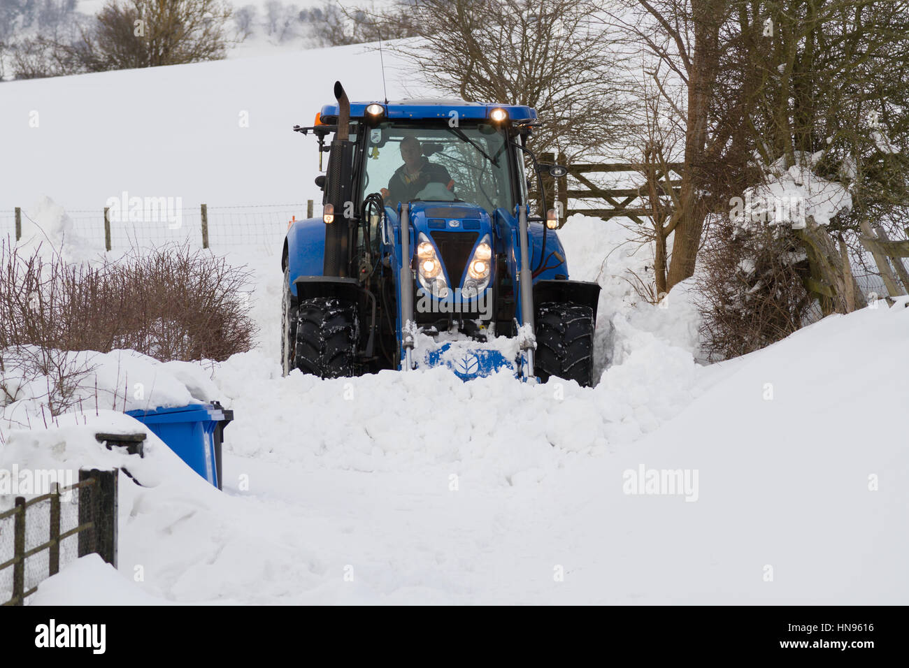 Il contadino si tenta di cancellare la neve profonda dopo una molto forti nevicate nelle zone rurali a Llangollen Galles del Nord Foto Stock