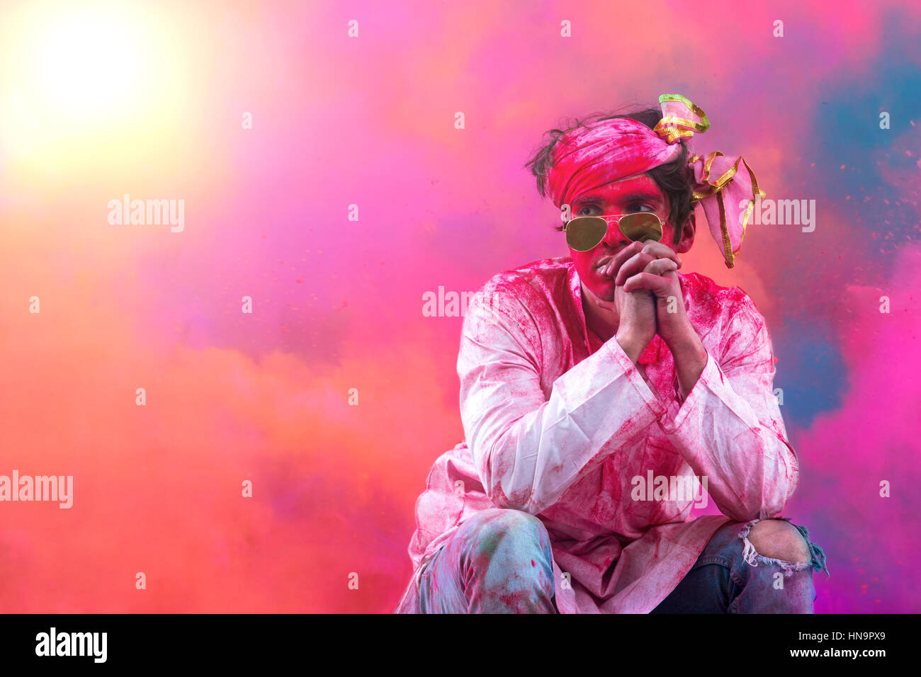 Giovani indiani uomo seduto su un banco di lavoro, coperto di polvere colorata durante Holi festival a colori Foto Stock