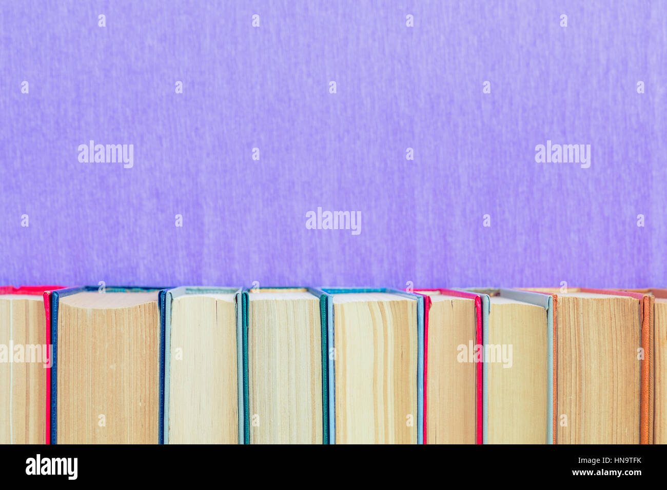 Libri sullo sfondo. Molti diversi libri sulla parete viola. Foto Stock