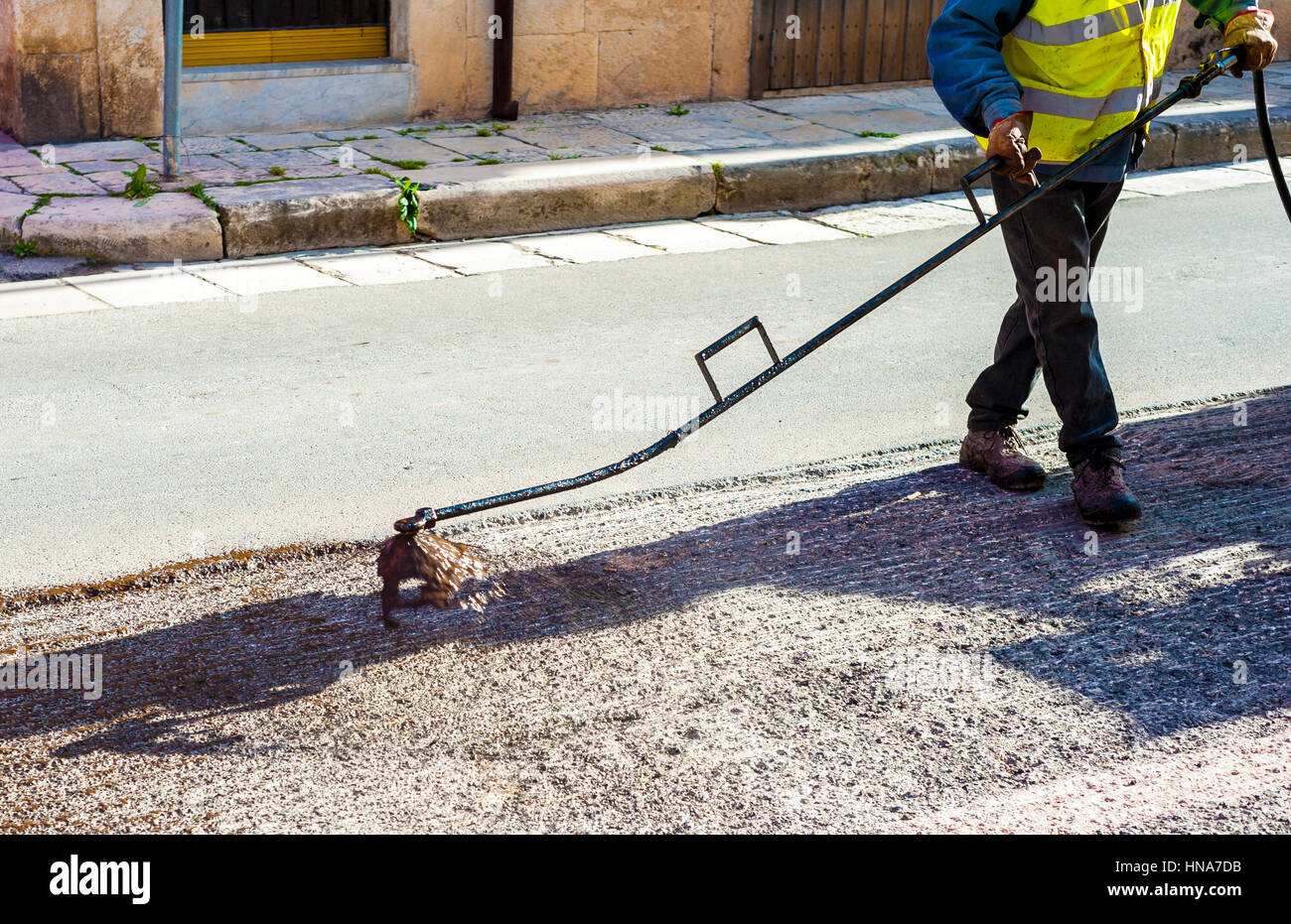 Lavoratore su strada la spruzzatura di emulsione di bitume con la mano lancia spray prima di applicare un nuovo strato di asfalto Foto Stock