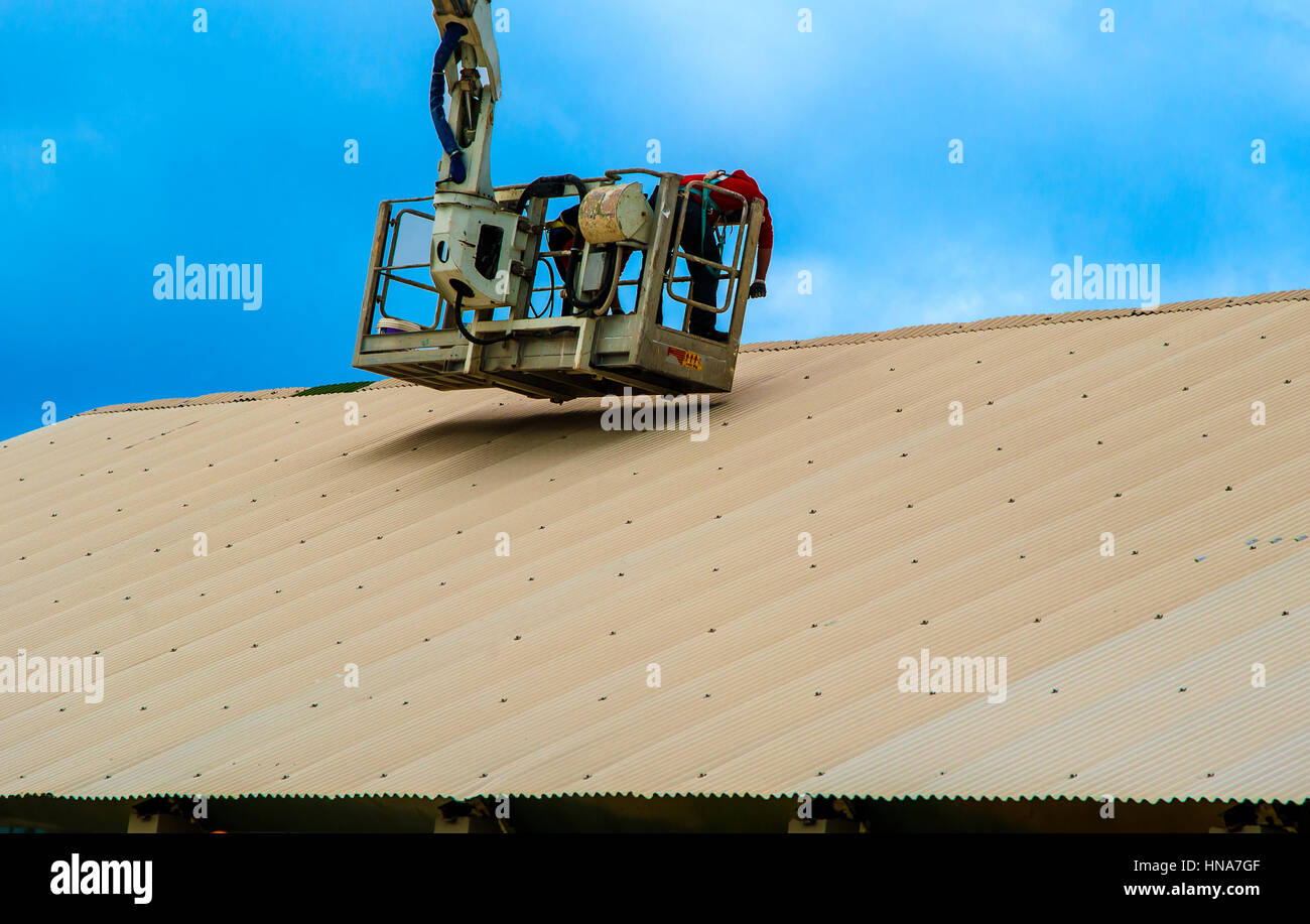 Le riparazioni del lavoratore coperchio di metallo su un piccolo cestino passeggero camion gru Foto Stock