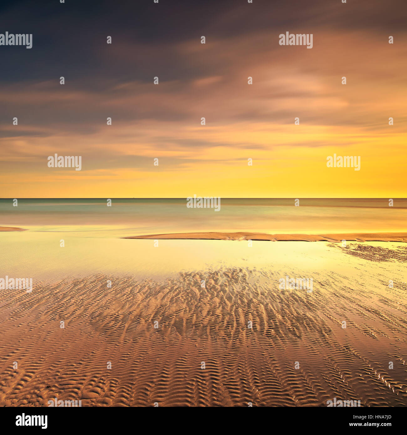 Ocean spiaggia sabbiosa di linea e caldo giallo rosso tramonto. Fotografie con lunghi tempi di esposizione Foto Stock