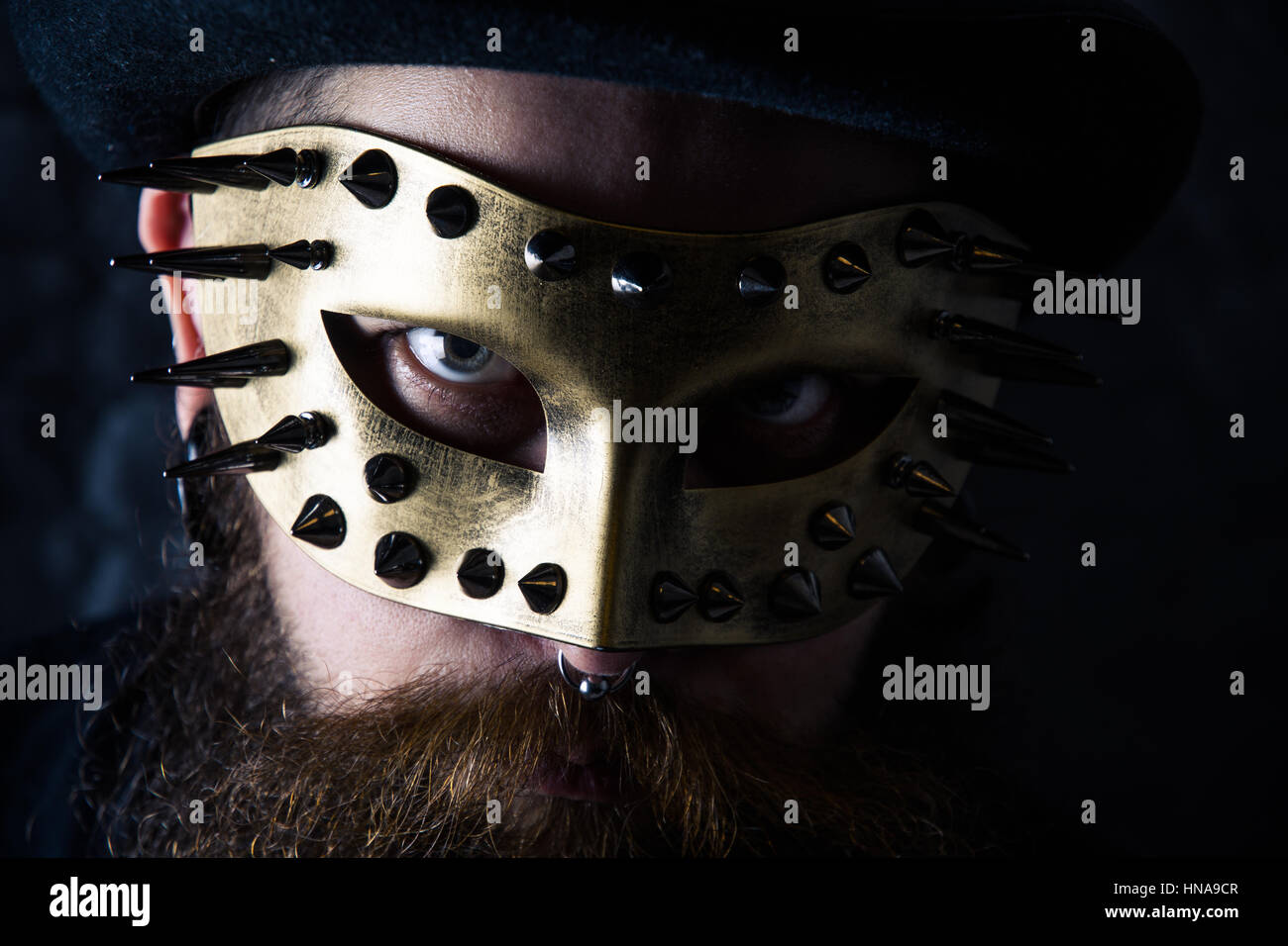 Primo piano di un uomo con un golden maschera chiodati Foto Stock