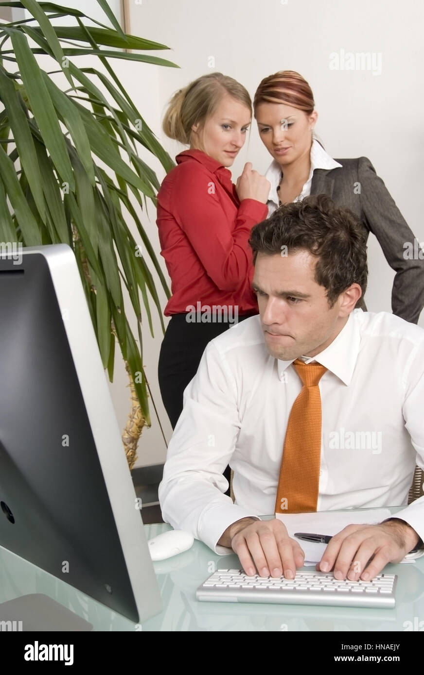 Symbolbild Mobbing am Arbeitsplatz, zwei Frauen reden hinter Ruecken dem des Arbeitskollegen miteinander - simbolico per mobbing al lavoro Foto Stock