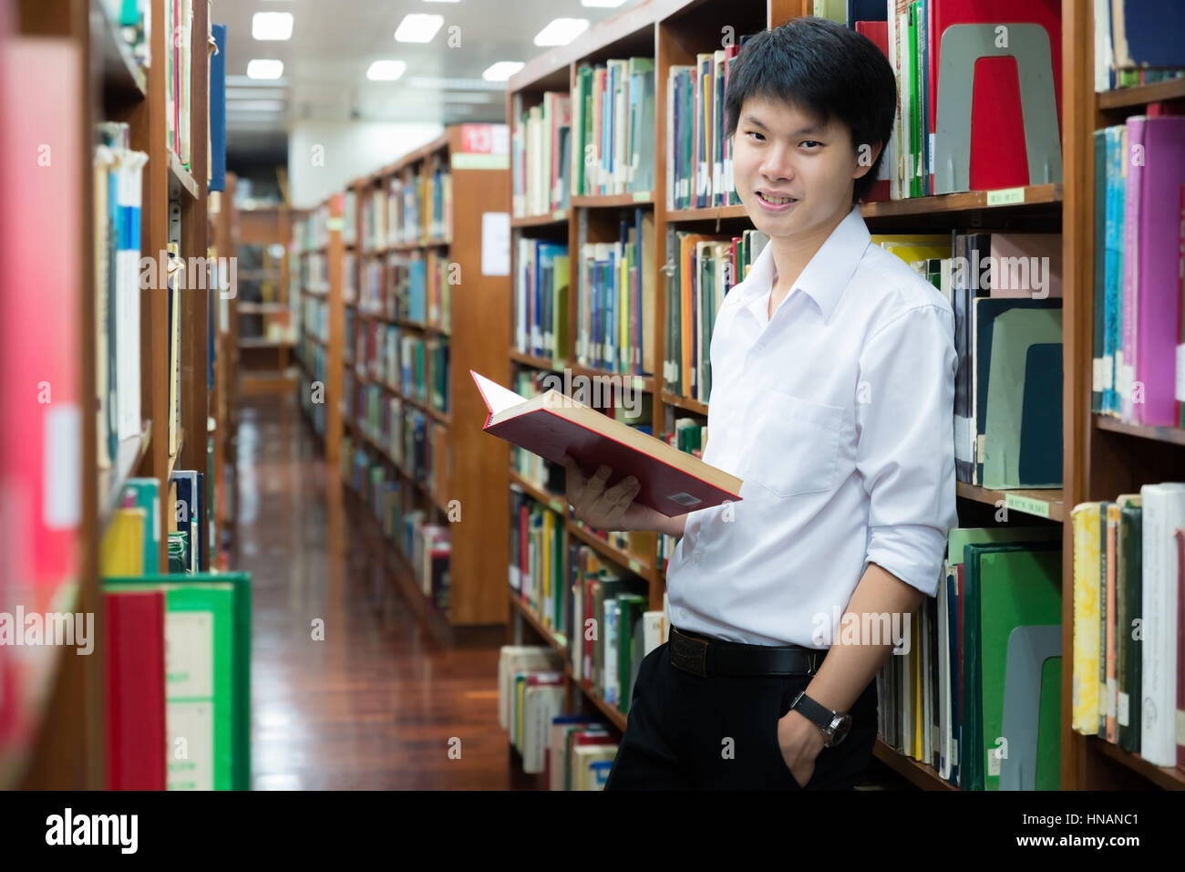 Asian studente in uniforme di lettura in biblioteca presso l' università Foto Stock