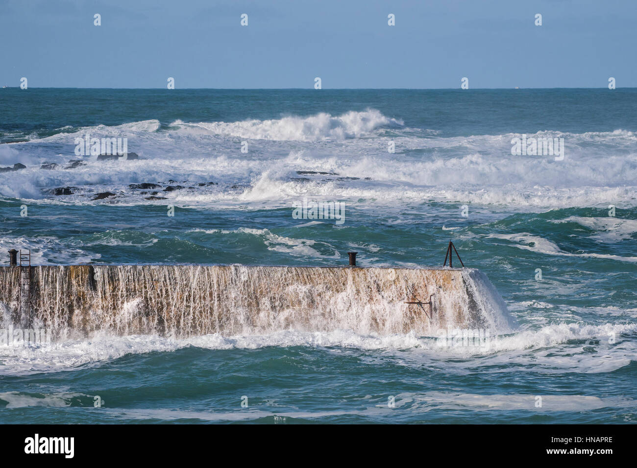 Alta venti onde di trasmissione sopra la parte superiore del frangiflutti in Sennen Cove, Cornwall, Inghilterra. Regno Unito Meteo. Foto Stock