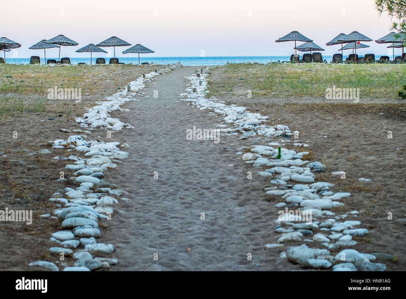 Una parete di roccia segnata strada fino alla spiaggia. Ci sono ombrelloni e lettini e lontano piccola area orizzontale, il mare è visibile. Foto viene scattata a Antalya, Turke Foto Stock