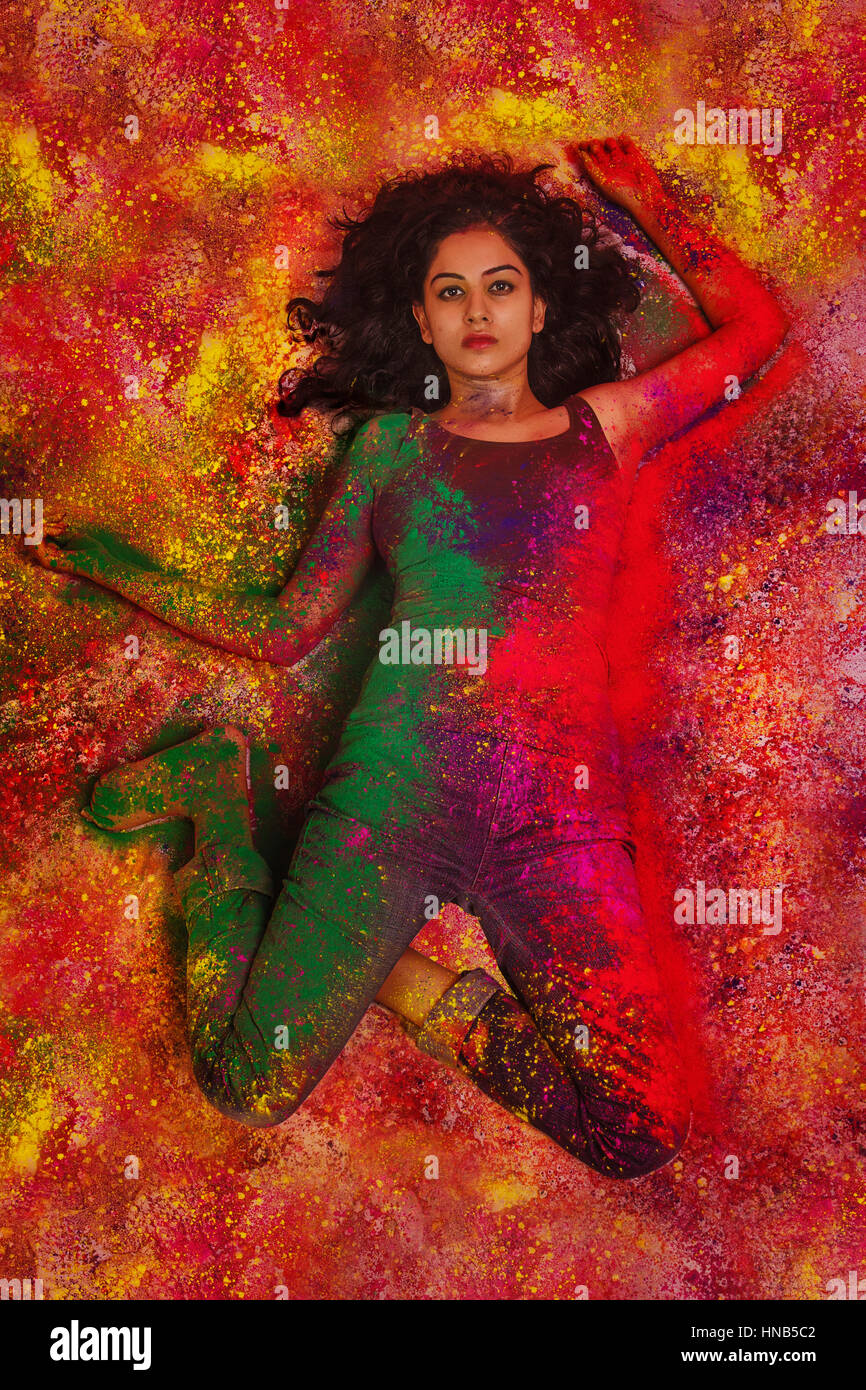 Elevato angolo di visione di un adolescente indiano ragazza distesa e coperto di polvere colorata durante Holi festival a colori Foto Stock