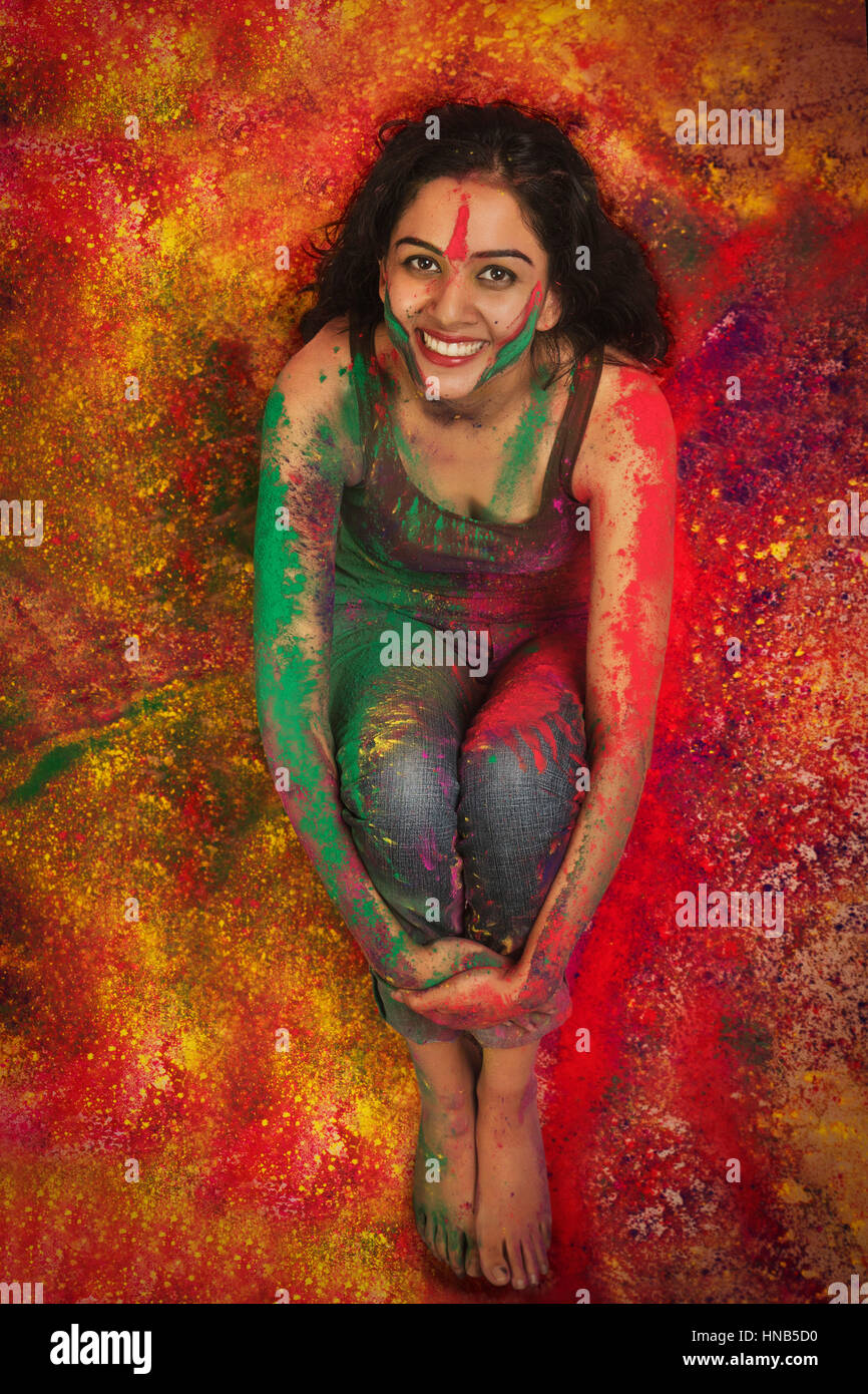 Elevato angolo di visione di un adolescente indiano ragazza seduta rivestita in polvere colorata durante Holi festival a colori Foto Stock