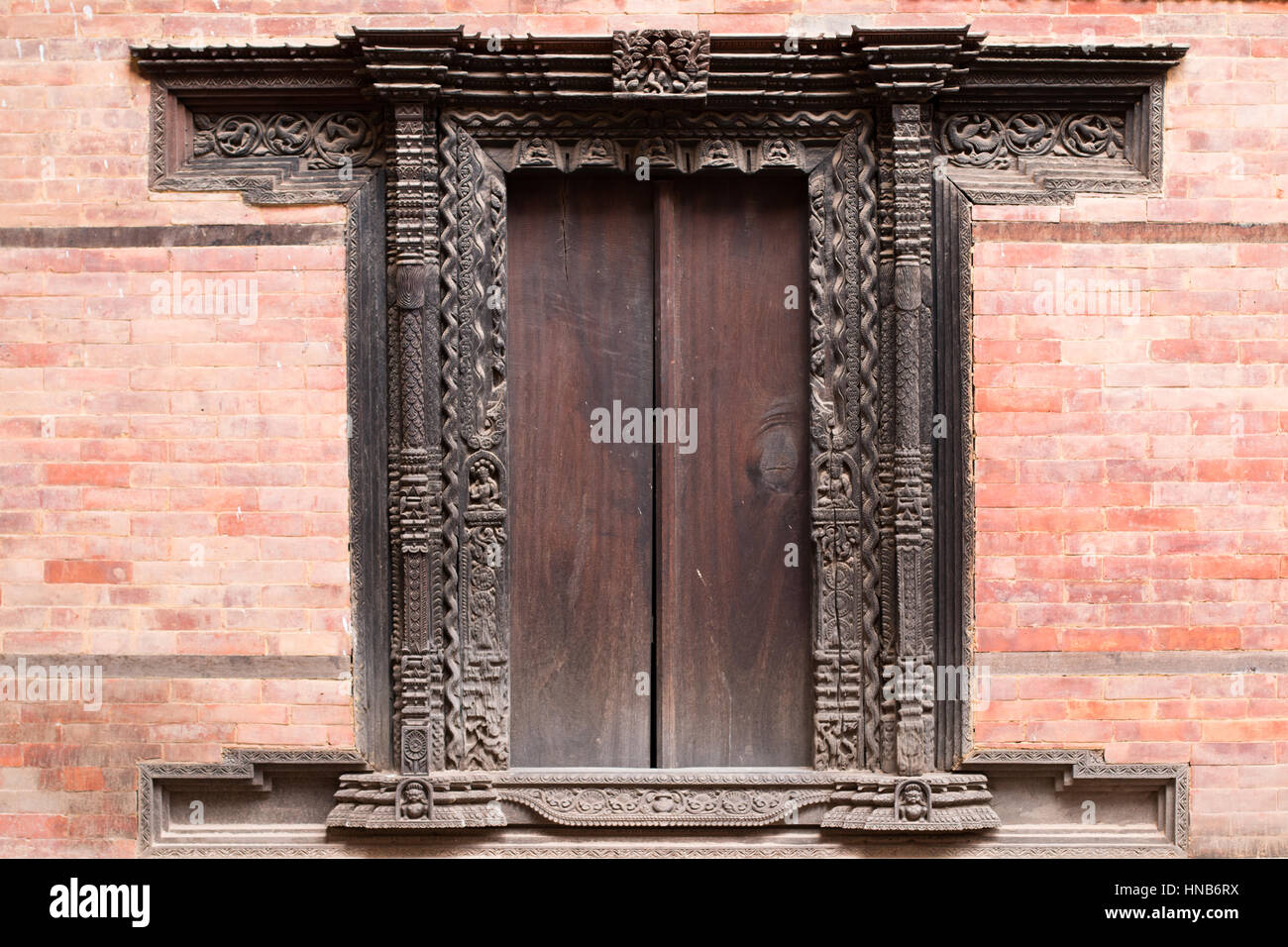 Riccamente intagliati teali in tradizionale stile nepalese di una porta in legno adornano un vecchio edificio in Bhaktapur, Kathmandu Foto Stock