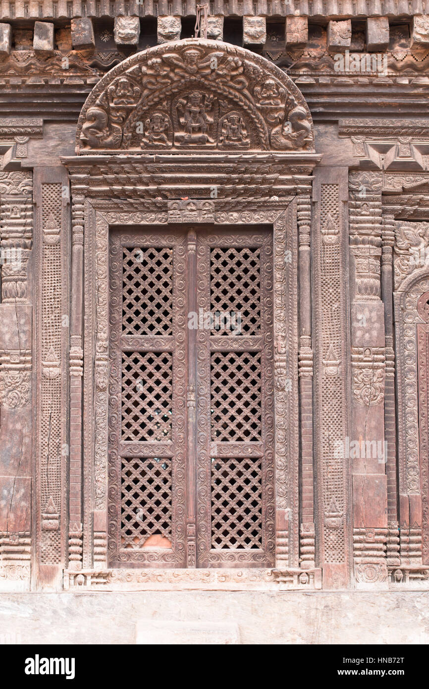 Riccamente intagliati lattic-lavoro porta di legno di una vecchia casa con un architrave in legno intagliato con divinità Indù in Bhaktapur, Kathmandu Foto Stock