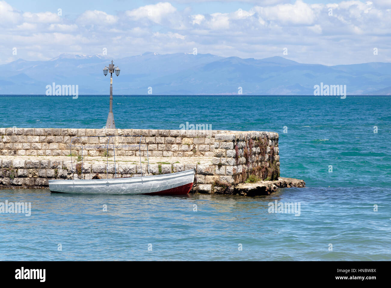 Bianco piccola barca a remi in barca ormeggiata presso il molo di pietra nel porto presso il lago di Ohrid Macedonia Foto Stock