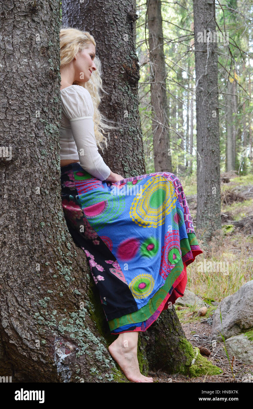 Donna seduta su un albero nella foresta Foto Stock