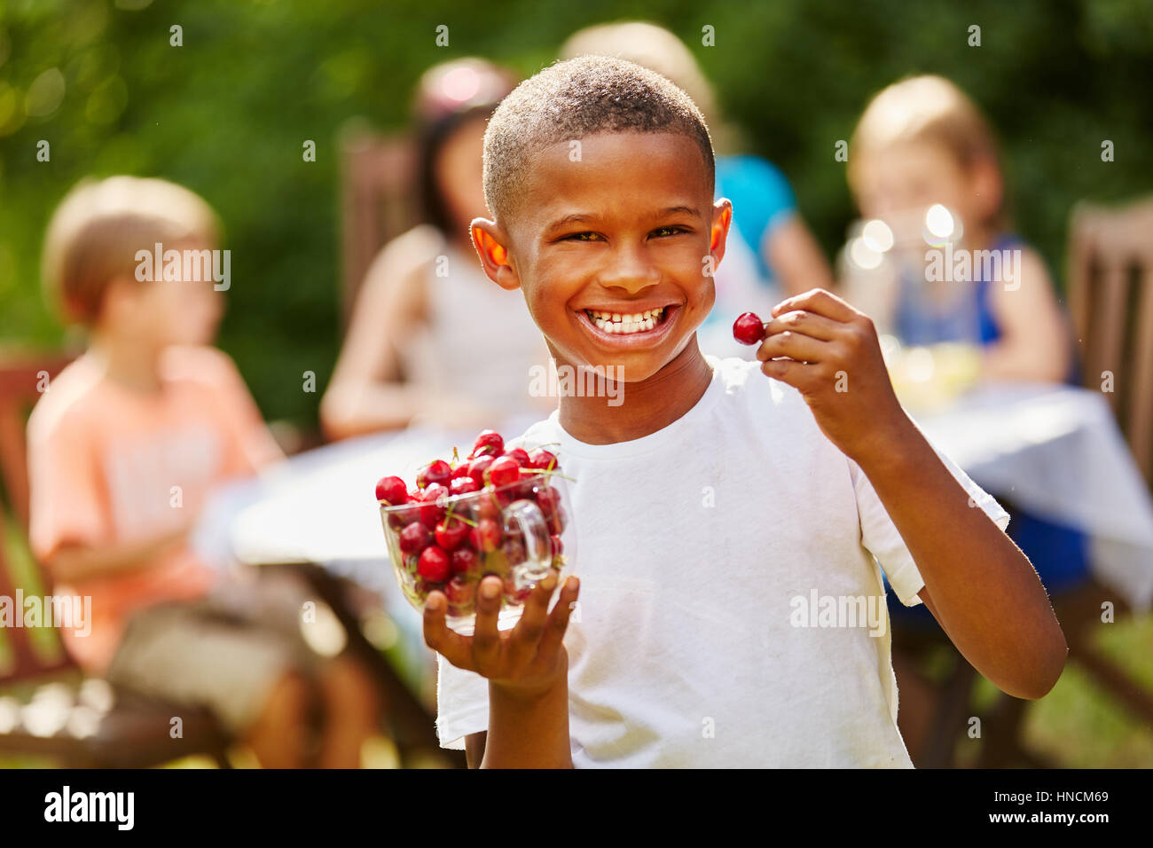 Ragazzo africano mangia ricco in vitamine le ciliegie di ridere con gioia Foto Stock