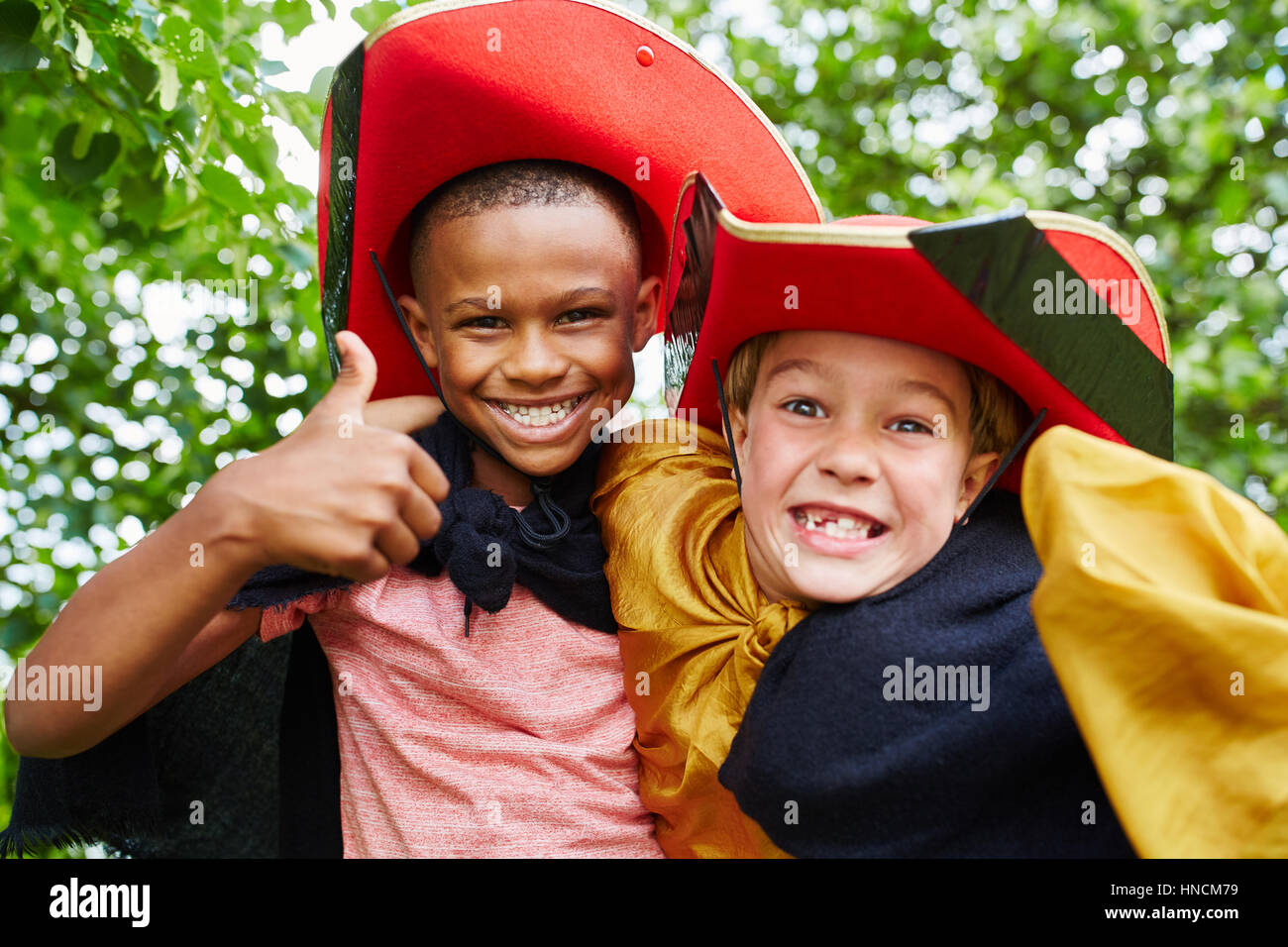 I bambini con i costumi tenendo pollice in alto e sorridente con gioia Foto Stock