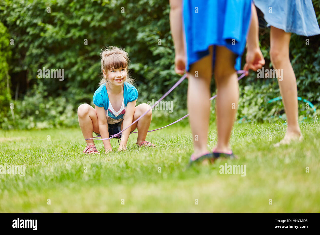 Bambini gioco chinese salto con la corda gioco con fascia di gomma in giardino Foto Stock