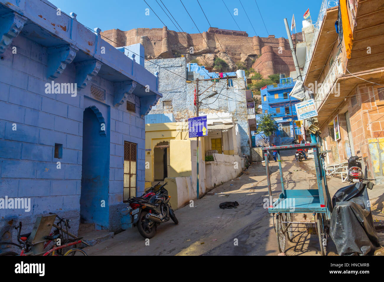 Una strada laterale in Jodhpur con il Forte Mehrangarh in background. Foto Stock