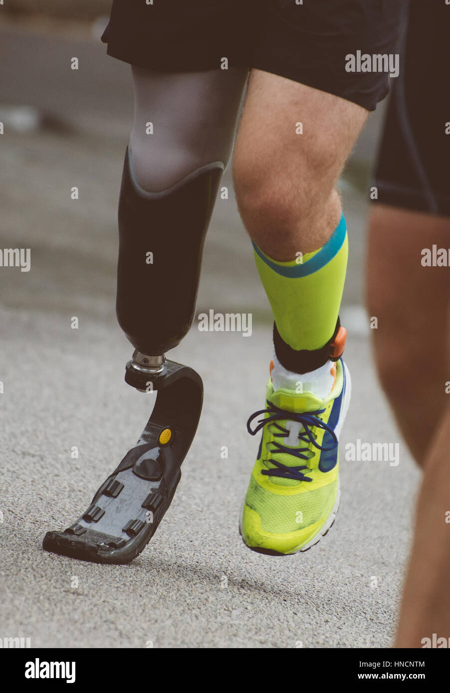 Running Man con gamba protesico su strada. Foto Stock