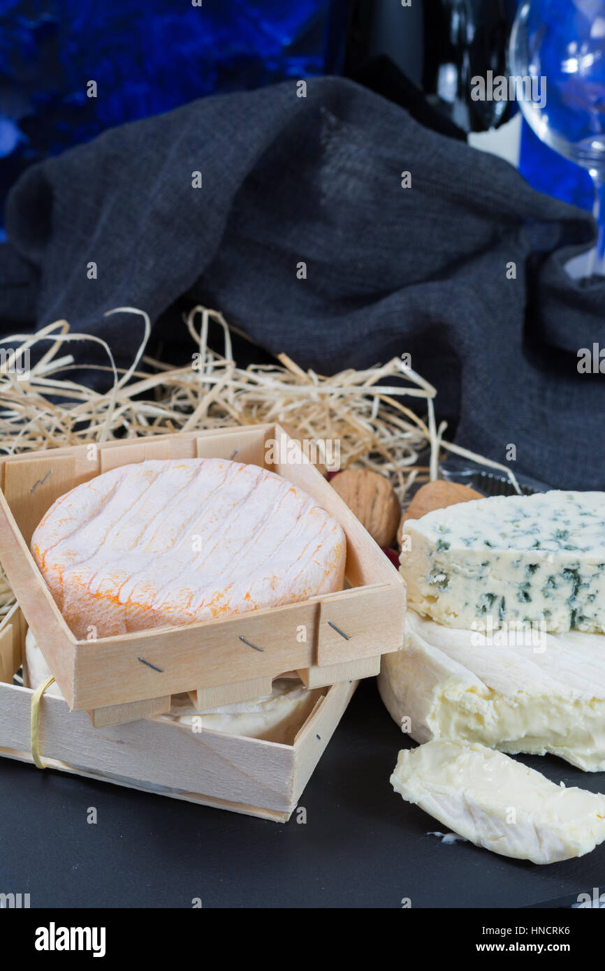 Il francese di formaggi molli sulla pietra nera del piatto e una bottiglia di vino rosso Foto Stock