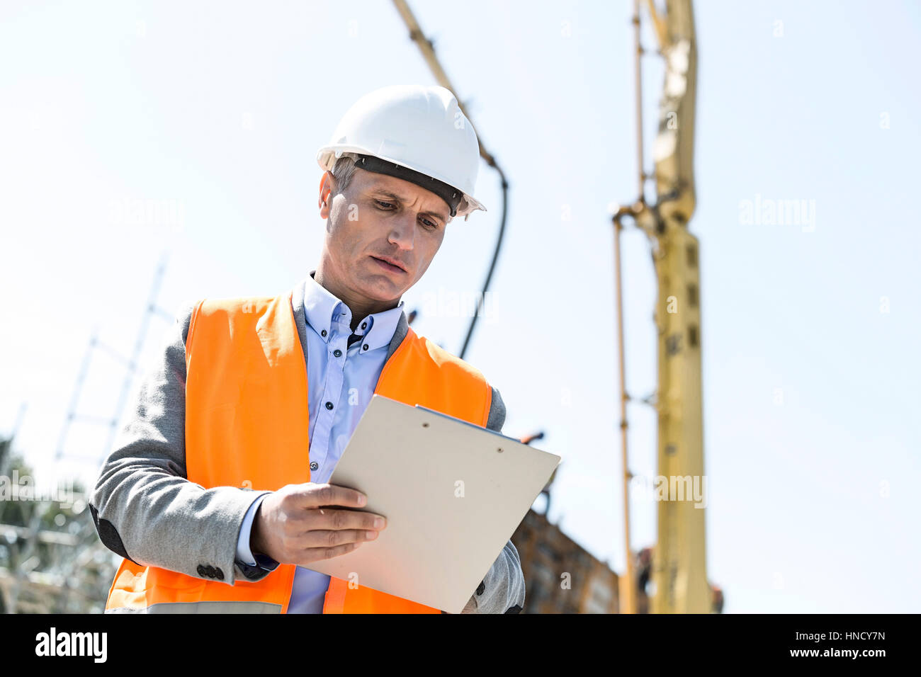 Basso angolo vista del supervisore sulla scrittura di appunti nel sito in costruzione Foto Stock