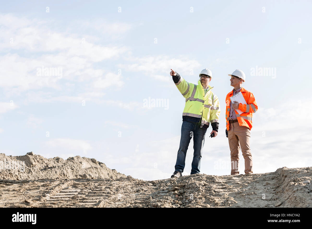 Basso angolo vista del supervisore che mostra qualcosa da un collega sul sito in costruzione Foto Stock