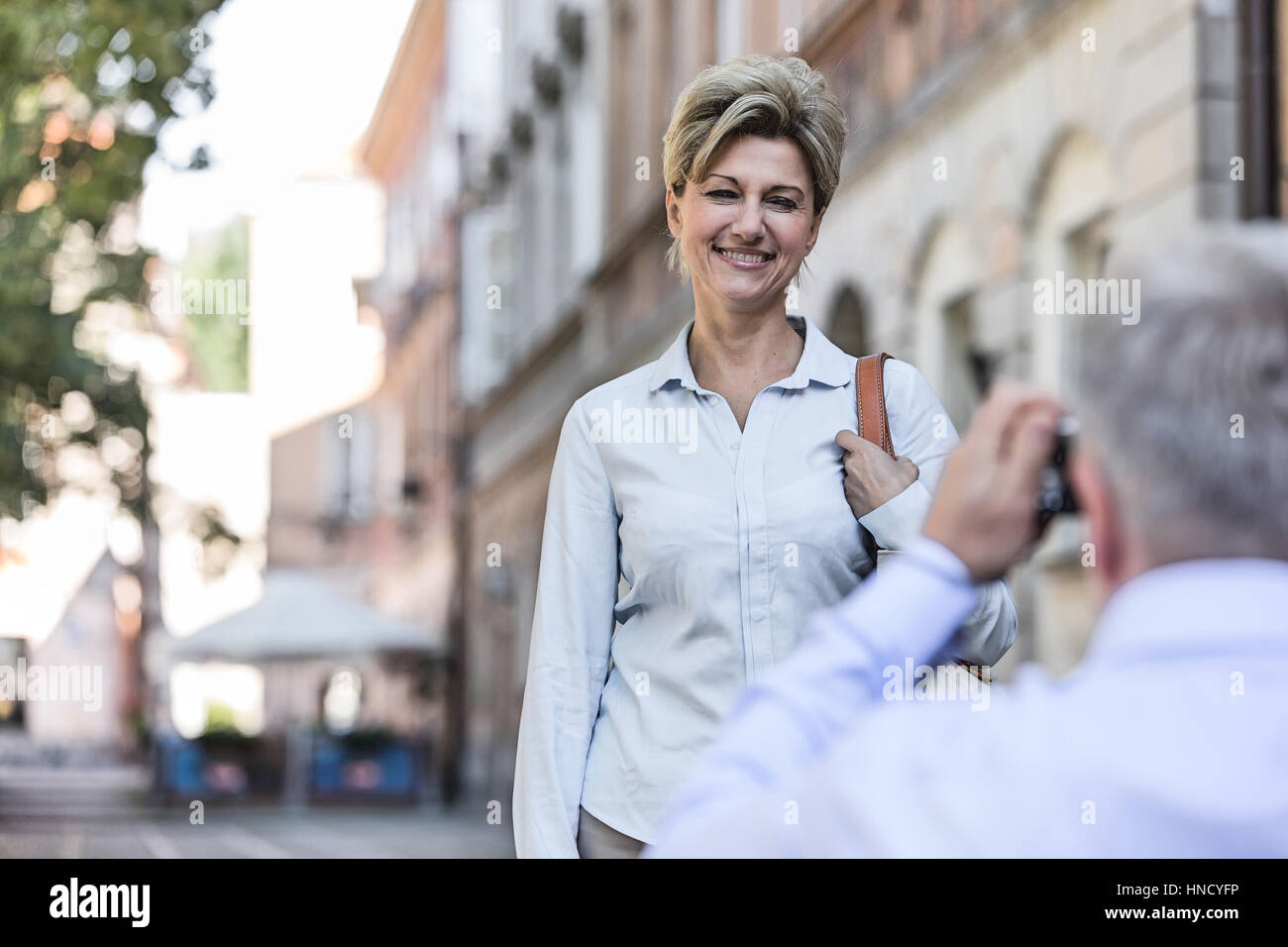 Uomo di mezza età sta immagine di donna in città Foto Stock
