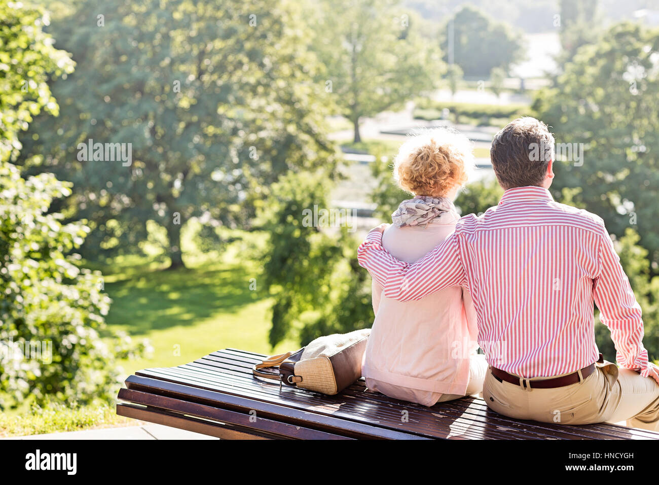 Vista posteriore di mezza età giovane relax su una panchina nel parco Foto Stock