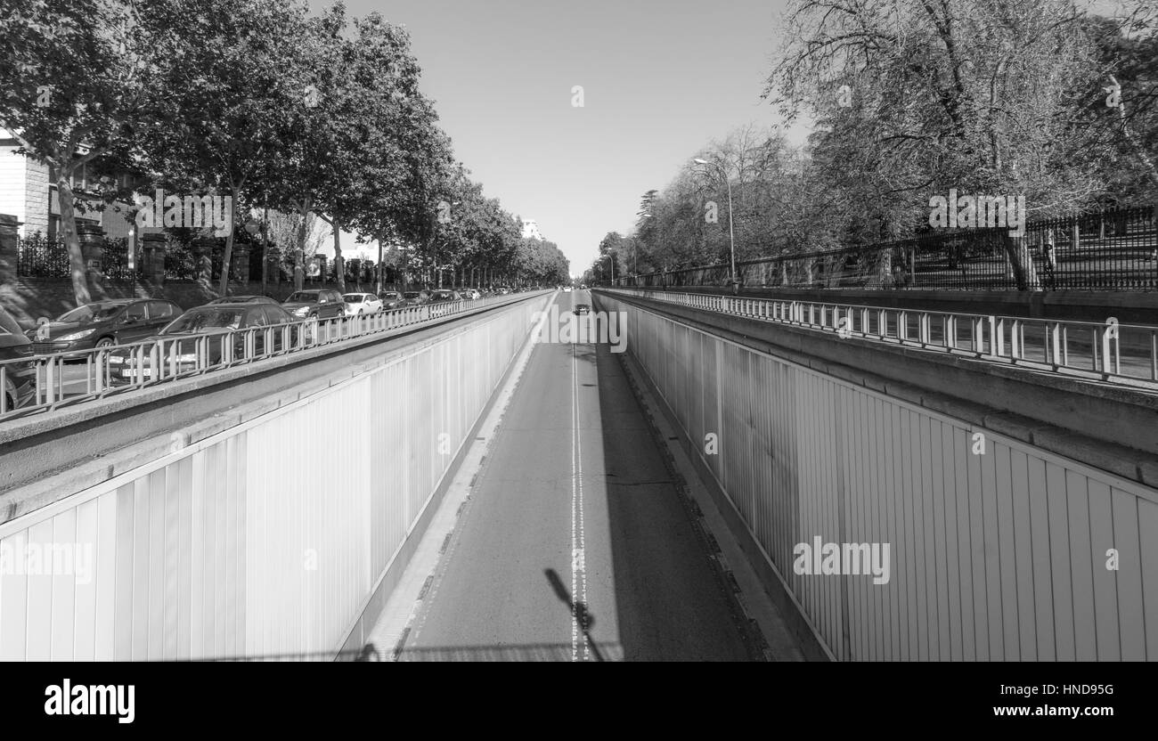 Black & White street scene in Madrid. Sun brilla luminosa su Calle del Alfonso dove si entra in un tunnel che corre sotto un'intersezione, sopra. Foto Stock