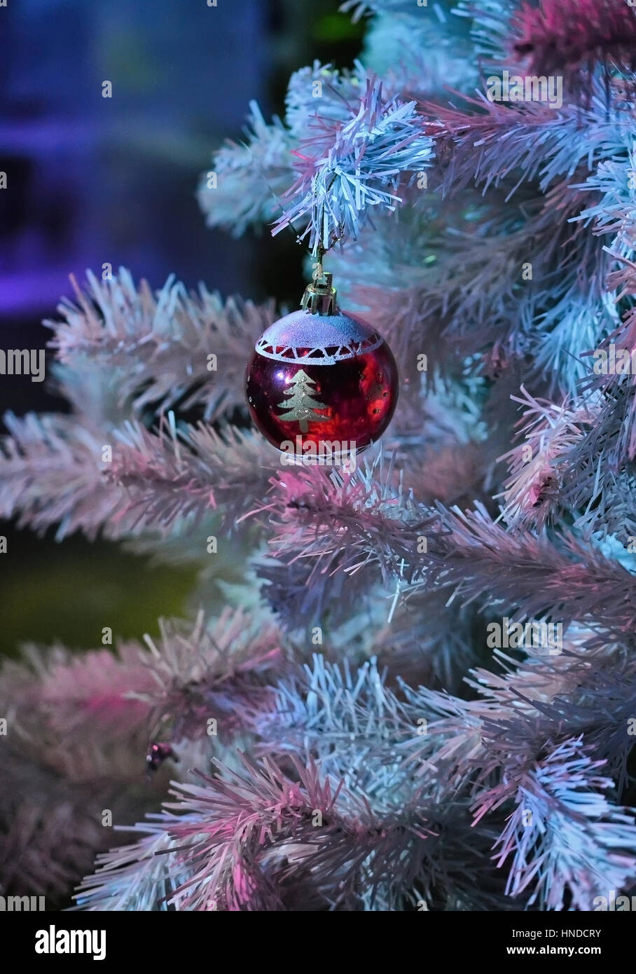 Giocattolo di natale - sfera rossa sull'albero di Natale artificiale. Foto Stock